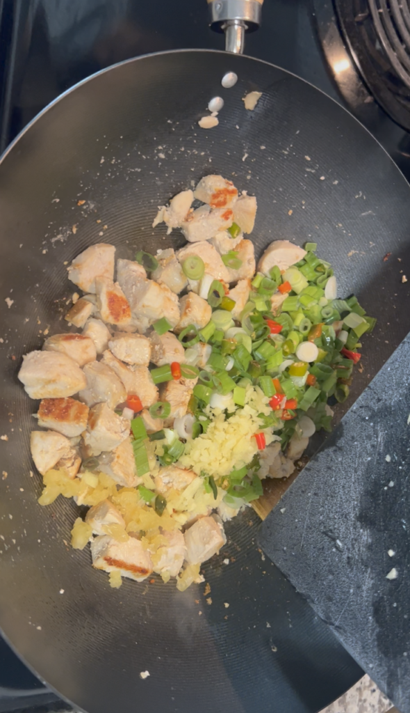 Adding the garlic, ginger, scallions, and Thai chilies.